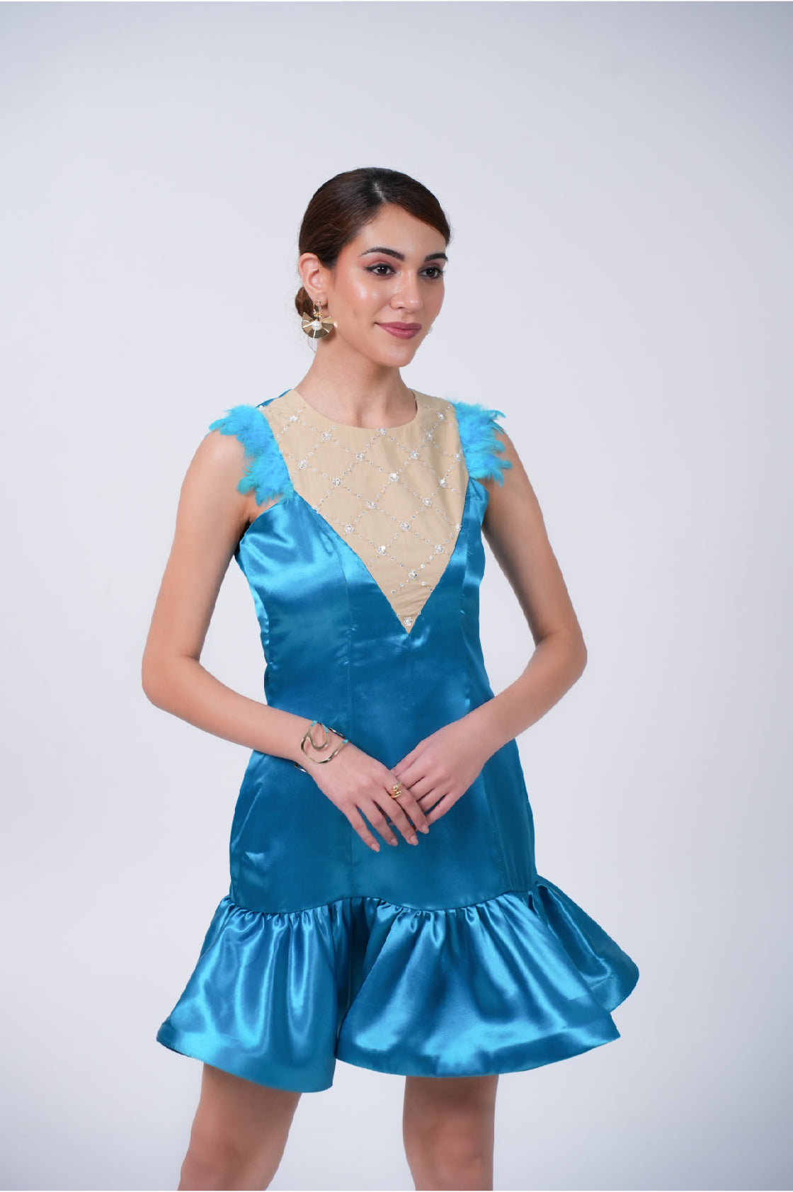 Woman wearing a blue mini dress with a beige neckline against a white background
